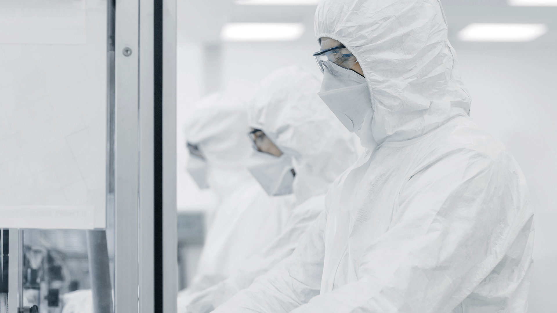 Three persons in cleanroom suits